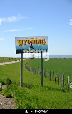 Benvenuti a stato del Wyoming a segno con il Wyoming paesaggio di pianura e le montagne sullo sfondo. Foto Stock