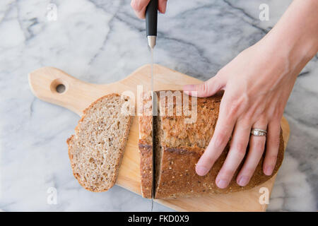 Close-up di donna di mani il pane di taglio Foto Stock