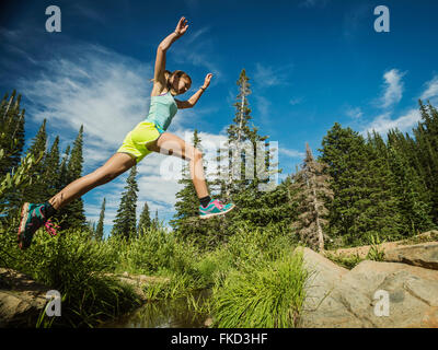 Ragazza adolescente (14-15) jumping in foresta Foto Stock