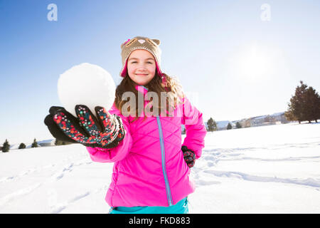 La ragazza (10-11) in camicia rosa azienda snowball Foto Stock