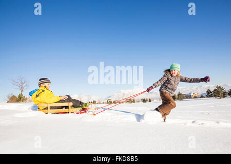 Bambini (8-9) giocando con slitta nella neve Foto Stock