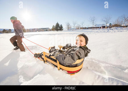 Bambini (8-9) giocando con slitta nella neve Foto Stock