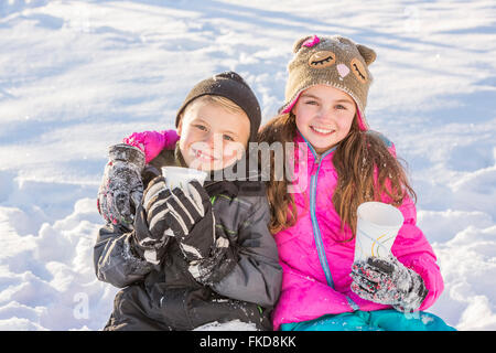 Ragazzo (8-9) e la ragazza (10-11) il riscaldamento di bere cioccolata calda Foto Stock