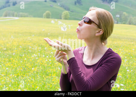 Donna che soffia sul dente di leone Foto Stock