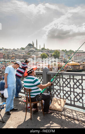 Uomo di pesca sul Ponte di Galata, Moschea Suleymaniye in background, Istanbul, Turchia Foto Stock