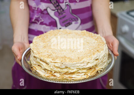 Torta 'Napoleone' su un vassoio nelle mani delle donne. Foto Stock