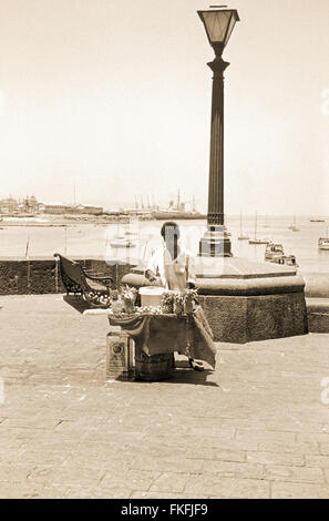 Straßenverkäufer auf dem Platz vor dem Gateway of India a Mumbai nel 1962, 1960s. Venditore vicino al Gateway of India. Foto Stock