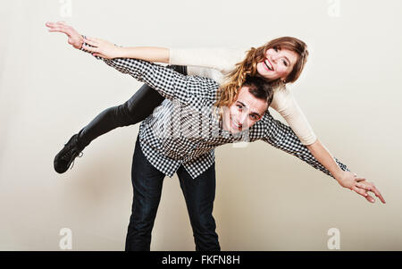 Amare le persone e la felicità oncept. Sorridente coppia giovane divertendosi, uomo dando piggyback ride per donna Foto Stock