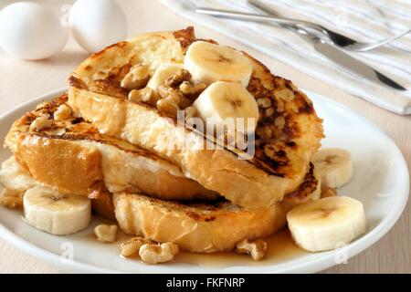 Piastra di deliziosi toast alla francese con banane, noci e gocce di sciroppo d'acero Foto Stock