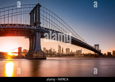 Manhattan Bridge framing skyline di New York al tramonto. Foto Stock
