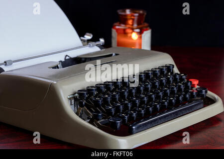 Vintage nastri inchiostratori per macchine da scrivere e la carta su un tavolo sotto lume di candela pronto per l'autore di scrivere una storia. Foto Stock