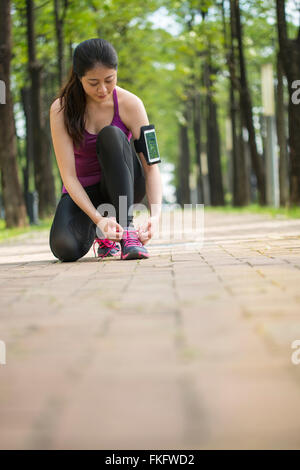 Asian giovane donna runner lacci delle scarpe di legatura su uno stile di vita sano jogging Foto Stock