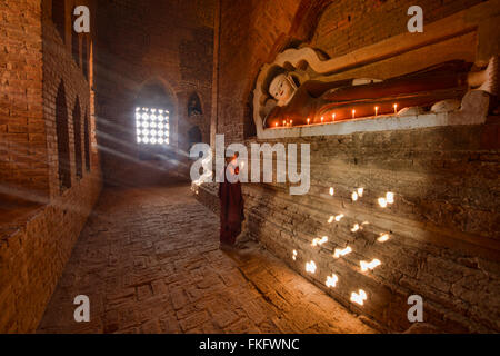 Un giovane monaco di pregare con i raggi del sole in templi di Bagan, Myanmar Foto Stock