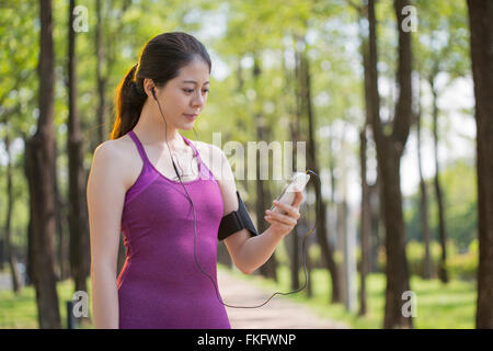 Sporty giovane donna asiatica ascoltando musica dopo il jogging nel bosco Foto Stock