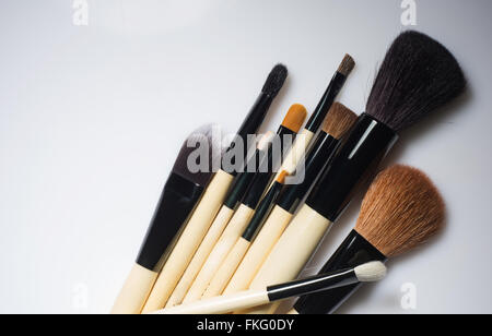 Mazzetto di make-up pennelli casualmente giacente su sfondo bianco. Foto Stock