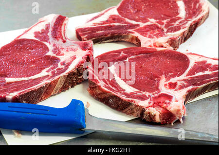 Tre crudo affettato fresco di tagli di carne sul tavolo di metallo accanto al coltello carving Foto Stock