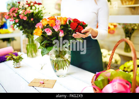 Close-up di fiorista femmina in piedi vicino al mazzo di rose Foto Stock