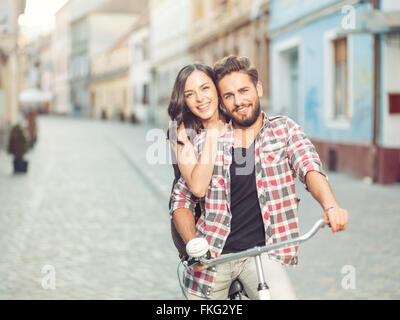 Bella coppia Giovane su una bicicletta nella città sorridente con positività vestiti casual Foto Stock