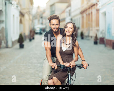Bella coppia Giovane su una bicicletta nella città sorridente con positività vestiti casual Foto Stock