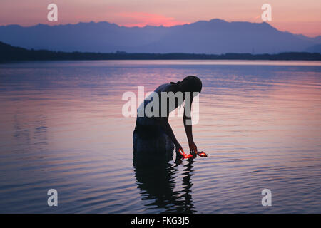 Silhouette di donna in viola le acque del lago con candele galleggianti . Bellezza e romanticismo concetto Foto Stock