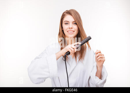 Bella felice giovane donna in accappatoio utilizzando capelli su sfondo bianco Foto Stock