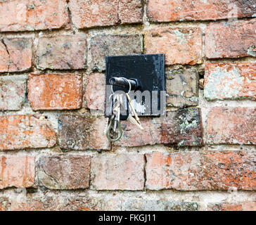 Un mazzo di chiavi appeso ad un gancio su un muro di mattoni Foto Stock