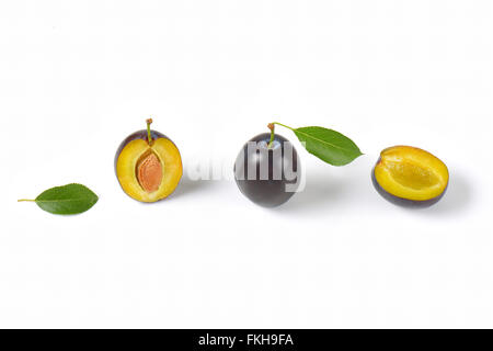 Intero e dimezzato le prugne su sfondo bianco Foto Stock