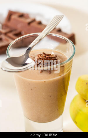 Un delizioso cioccolato frullato di banane in un bicchiere con un cucchiaio. Foto Stock