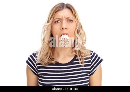 Studio shot di una giovane donna con un mucchio di sigarette nella sua bocca isolati su sfondo bianco Foto Stock