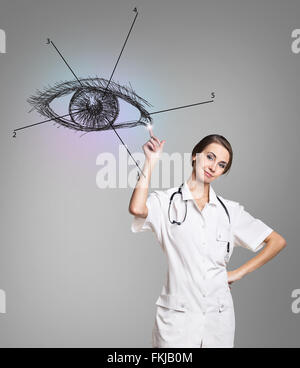 Medico donna in uniforme toccare dipinto occhio umano Foto Stock