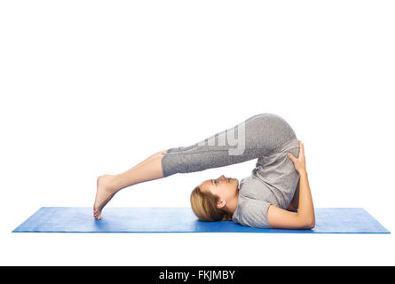 Donna fare yoga in aratro pone sul tappeto Foto Stock