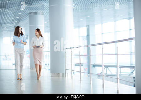 Due belle imprenditrici a camminare lungo il corridoio e la comunicazione Foto Stock