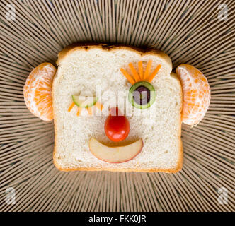 Felice faccia il pane fatto con la frutta e le verdure su sfondo astratto Foto Stock