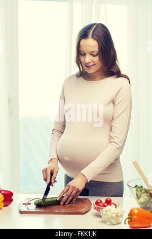 Felice donna incinta la preparazione di cibi a casa Foto Stock