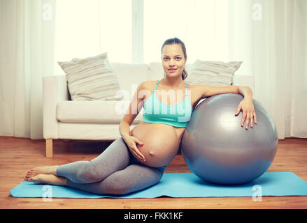 Felice donna incinta con fitball a casa Foto Stock
