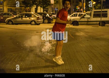 Ragazzo esplodere petardi durante la notte per celebrare la festa di sant Joan su una strada di Barcellona e della Catalogna, Spagna Foto Stock