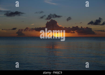 Tramonto a Rodney Bay, St Lucia. Un solitario yacht stagliano contro un tramonto e nuvole basse. Foto Stock