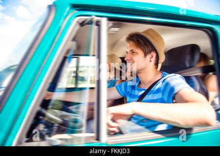 Hipster boy il pilotaggio di un vecchio camper con adolescenti, roadtrip Foto Stock