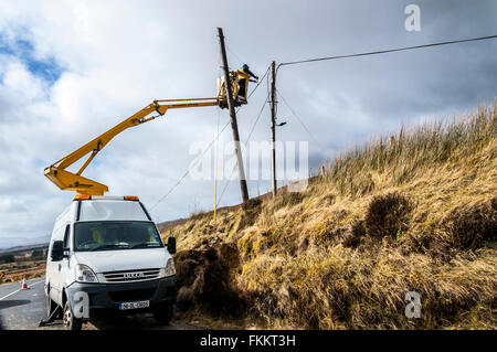 Un uomo lavora sul cavo telefonico pole rinnovamento in Irlanda rurale vicino a Glenties, County Donegal Foto Stock