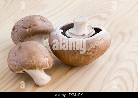 Tre funghi castagne su di un tagliere di legno Foto Stock