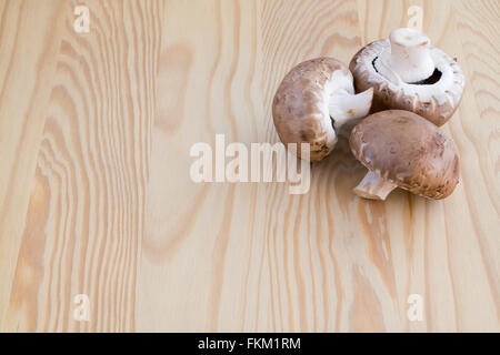 Tre funghi castagne su di un tagliere di legno Foto Stock