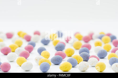 Un sacco di piccolo, colorato, cioccolato, caramelle uova di pasqua sparsi su un fondo bianco con copia spazio sopra. Foto Stock