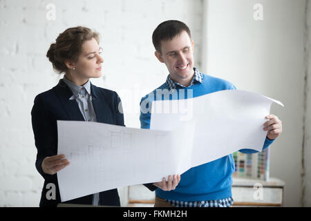 Due colleghi alla riunione per discutere concept per il nuovo progetto e tenendo blueprint, lavori di pianificazione. Discussione aziendale Foto Stock