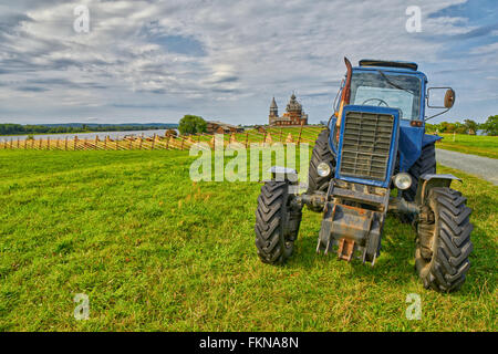 Vecchio arrugginito trattore su un campo con il monastero in background in isola di Kizhi, Russia Foto Stock