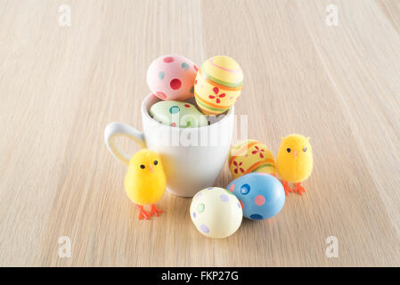 Pasqua, piccolo pulcino e uova colorate in una tazza di caffè Foto Stock