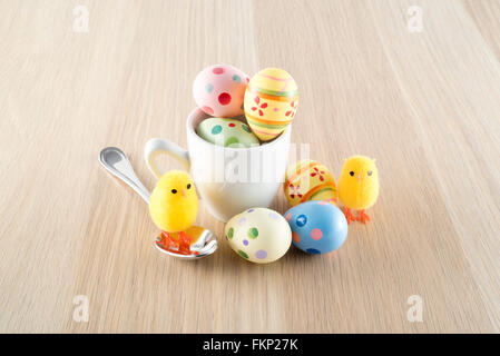 Pasqua, piccolo pulcino e uova colorate in una tazza di caffè Foto Stock