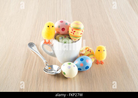 Pasqua, piccolo pulcino e uova colorate in una tazza di caffè Foto Stock
