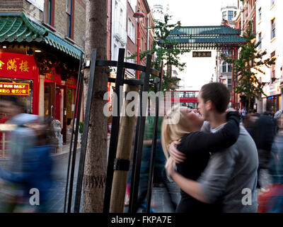 Giovane coppia corteggiamento abbracciando in una strada trafficata ignorassero i passanti. Chinatown London REGNO UNITO Foto Stock