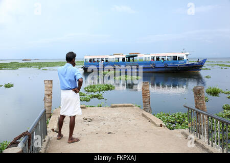 Il Kerala Backwaters, un uomo appena perso un trasporto pubblico in barca e in attesa per il prossimo viaggio a Kerala Foto Stock