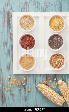 Vari tipi di grani in ciotole ( la quinoa,amaranto, miglio, chia,grano saraceno ) con riso, ceci e il mais accanto a bocce Foto Stock
